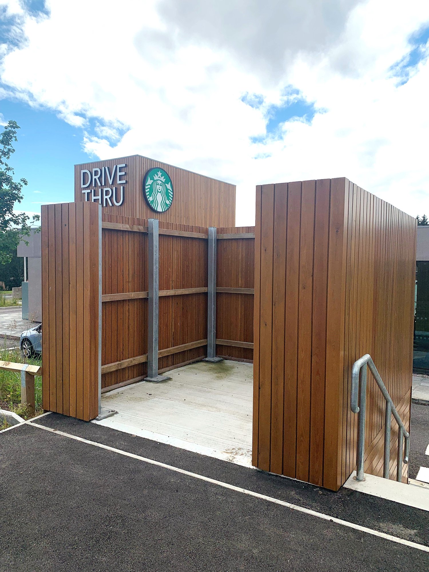 Bin store enclosure with galvanised mild steel posts and dressed timber slats stained to match the building.