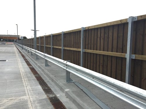 Corrugated beam barrier protecting an acoustic fence.